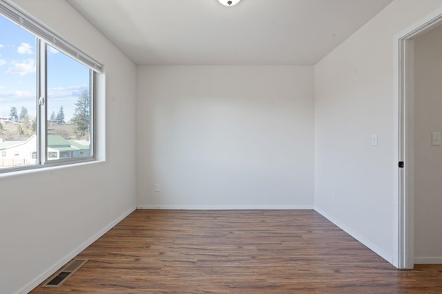 spare room with visible vents, dark wood finished floors, and baseboards