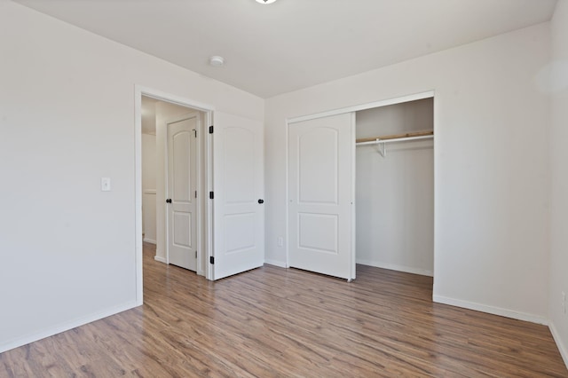 unfurnished bedroom with a closet, baseboards, and wood finished floors