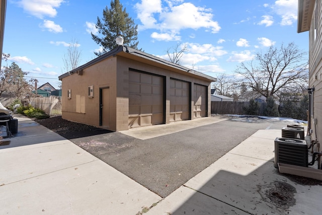 detached garage with fence and central AC unit