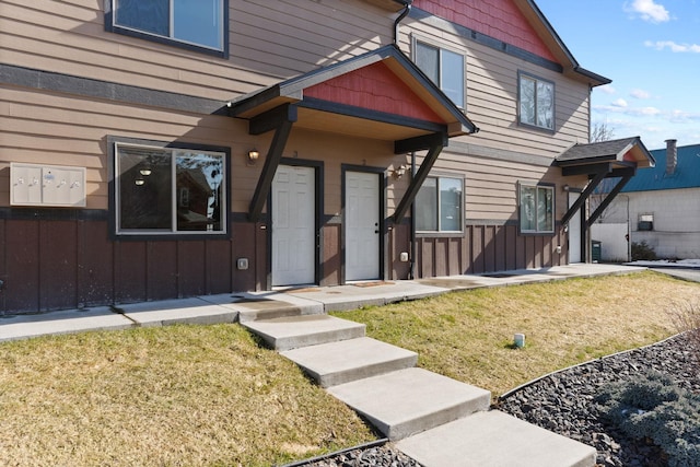 doorway to property featuring board and batten siding and a yard