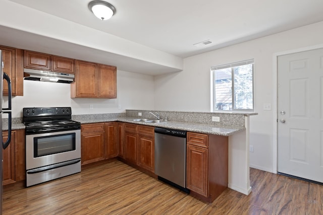 kitchen featuring brown cabinets, appliances with stainless steel finishes, a sink, and under cabinet range hood