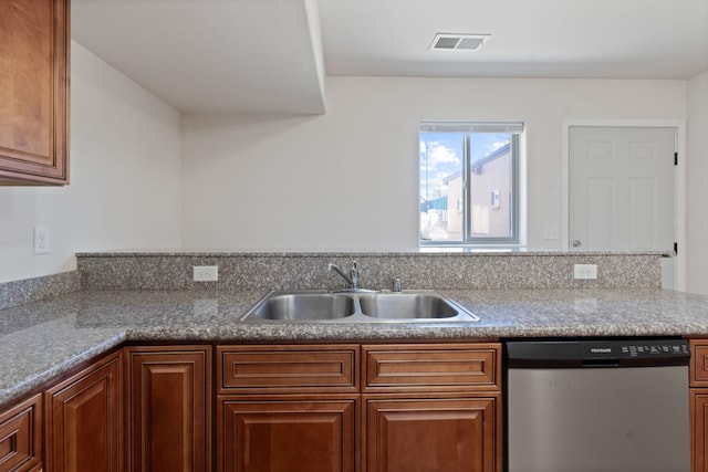 kitchen with a sink, visible vents, brown cabinets, and stainless steel dishwasher