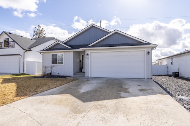 ranch-style house featuring roof with shingles, an attached garage, fence, cooling unit, and driveway