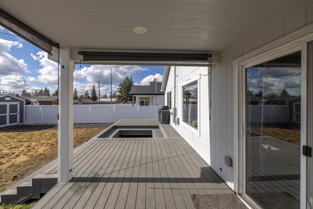 deck featuring a shed, a fenced backyard, and an outbuilding