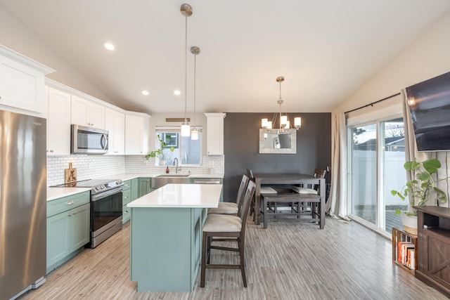 kitchen featuring lofted ceiling, stainless steel appliances, a sink, white cabinetry, and light countertops