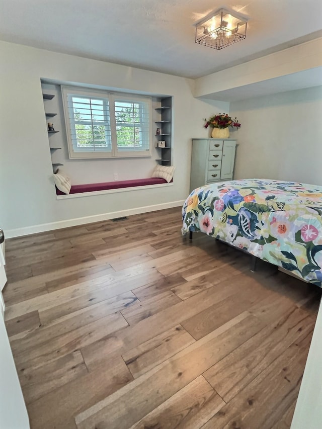 bedroom featuring a chandelier, baseboards, visible vents, and hardwood / wood-style floors