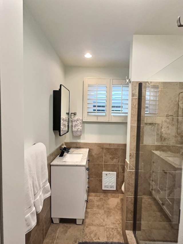 bathroom with visible vents, tile patterned floors, vanity, a shower stall, and tile walls