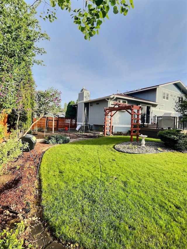 rear view of house with a deck, a lawn, and fence