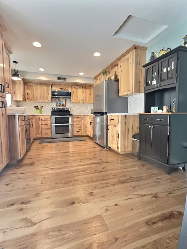 kitchen with stainless steel appliances, light brown cabinetry, ventilation hood, and light countertops