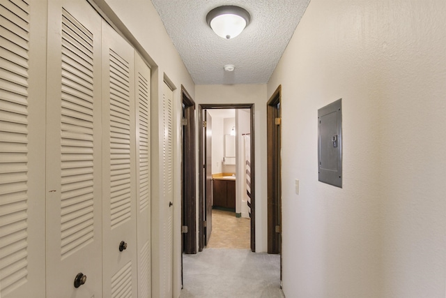 hallway featuring electric panel, a textured ceiling, and light colored carpet