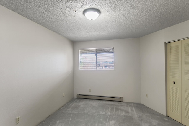 carpeted empty room featuring a textured ceiling and baseboard heating