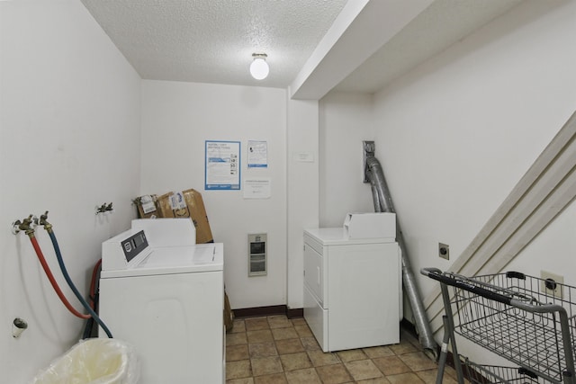 washroom with a textured ceiling, washing machine and clothes dryer, and baseboards