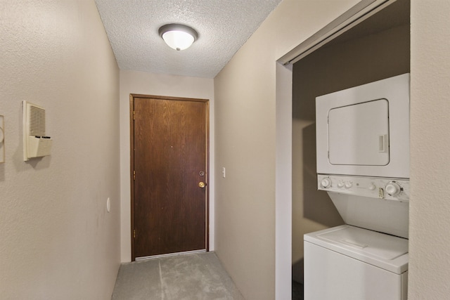 clothes washing area with stacked washer / drying machine, laundry area, a textured ceiling, and carpet