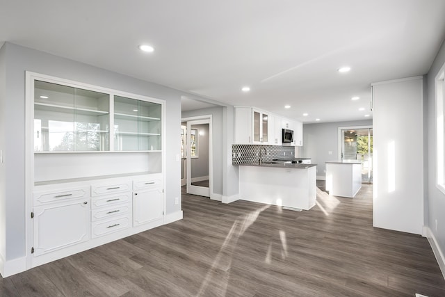 kitchen featuring dark wood-type flooring, stainless steel microwave, glass insert cabinets, and white cabinets