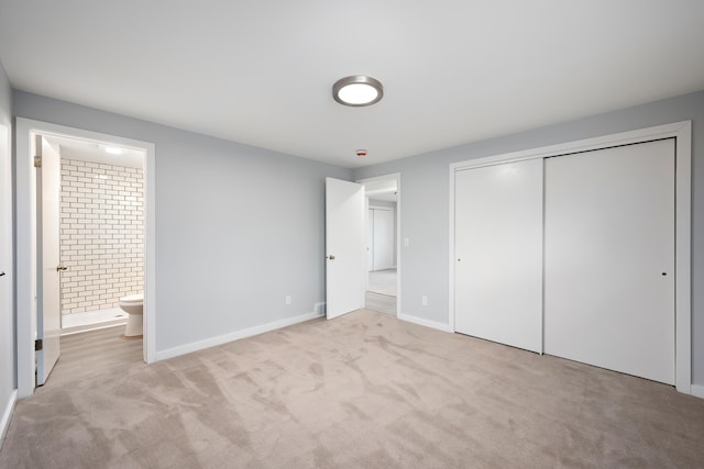 unfurnished bedroom featuring a closet, carpet, ensuite bath, and baseboards