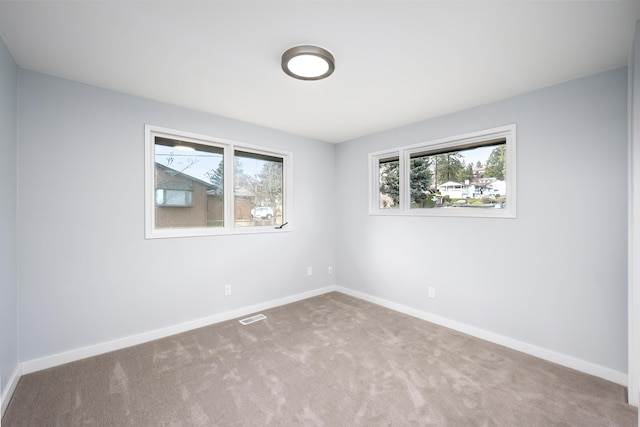 empty room featuring carpet, visible vents, and baseboards