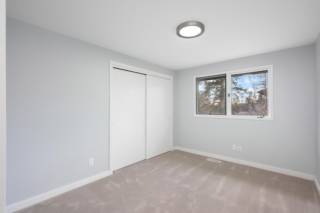 unfurnished bedroom featuring a closet, carpet flooring, visible vents, and baseboards