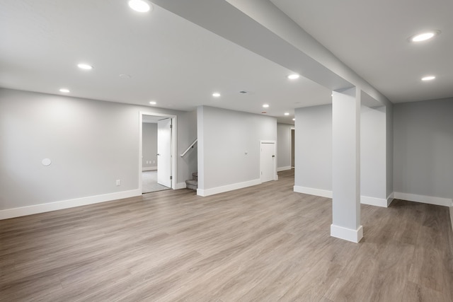 finished basement featuring recessed lighting, baseboards, stairway, and light wood finished floors