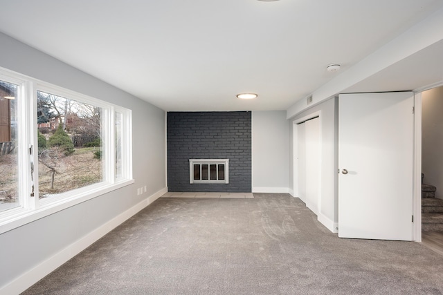 unfurnished living room with stairs, carpet floors, a brick fireplace, and baseboards