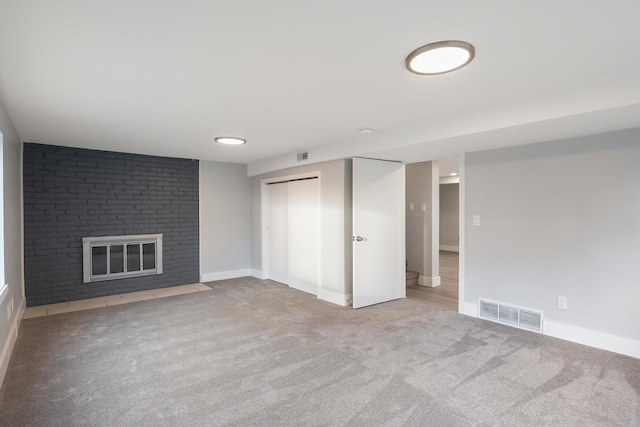 finished basement featuring carpet floors, a fireplace, and visible vents