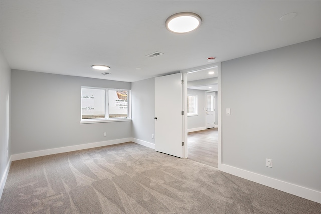 unfurnished room featuring carpet floors, visible vents, and baseboards