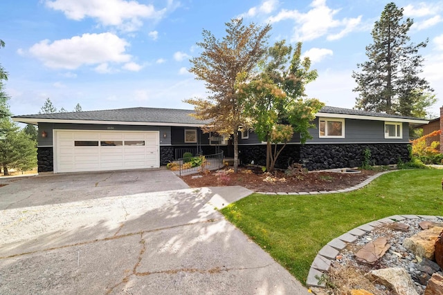 ranch-style house featuring a garage, stone siding, driveway, and a front lawn