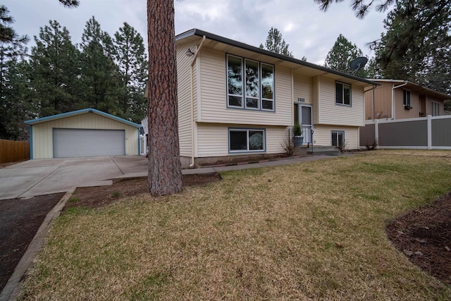 raised ranch featuring an outbuilding, a front yard, fence, and a detached garage