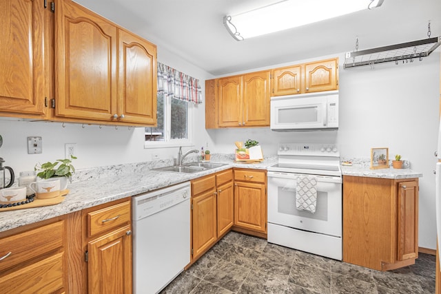 kitchen with white appliances, stone finish flooring, brown cabinets, and a sink