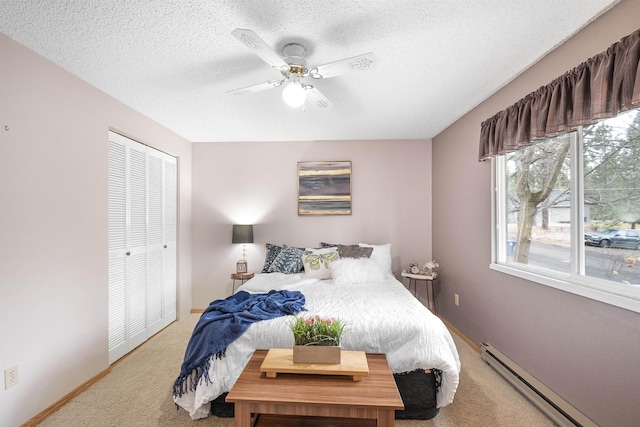 bedroom featuring a baseboard heating unit, carpet flooring, ceiling fan, a textured ceiling, and baseboards