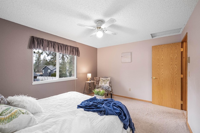 bedroom with a textured ceiling, a ceiling fan, baseboards, carpet, and attic access