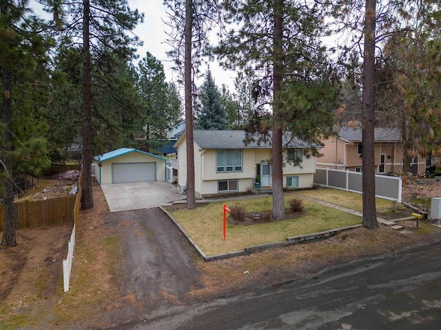 bi-level home featuring a garage, an outbuilding, fence, and a front lawn