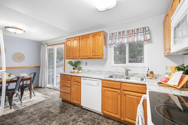 kitchen featuring white appliances, a textured ceiling, light countertops, and a sink