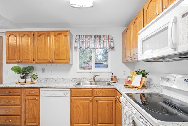 kitchen featuring white appliances, brown cabinetry, and a sink