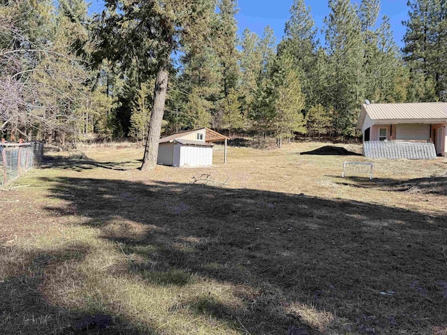 view of yard with an outbuilding, fence, and a shed