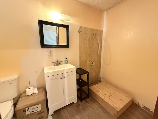 bathroom featuring a shower, vanity, toilet, and wood finished floors