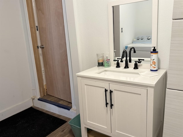 bathroom with washer / clothes dryer, vanity, and wood finished floors