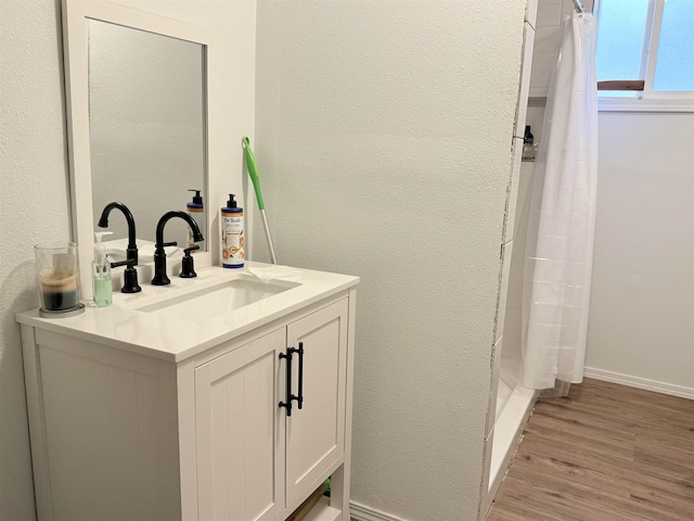 full bathroom featuring a shower with curtain, a textured wall, vanity, and wood finished floors