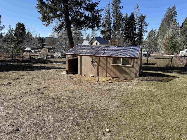 view of outdoor structure featuring solar panels and fence