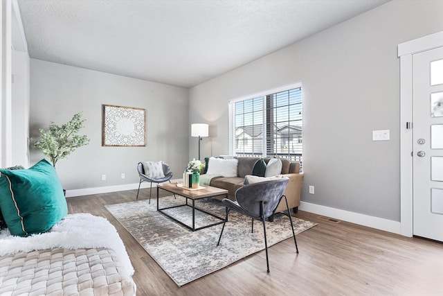 living area with wood finished floors, visible vents, and baseboards