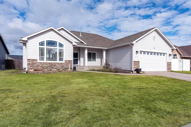 view of front of home featuring concrete driveway, fence, a garage, stone siding, and a front lawn