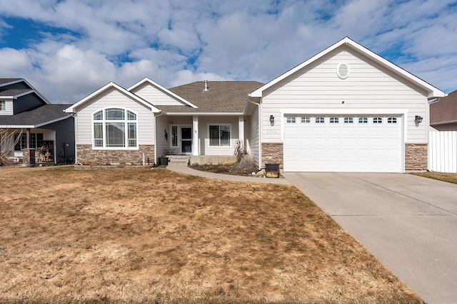 view of front facade with a front lawn, stone siding, driveway, and an attached garage