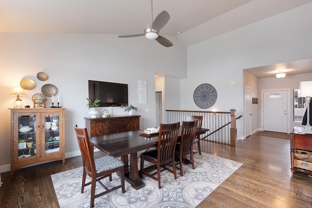 dining space with high vaulted ceiling, wood finished floors, a ceiling fan, and baseboards