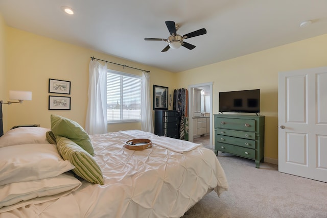 bedroom with ensuite bathroom, a ceiling fan, and light colored carpet