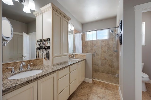 bathroom with a stall shower, a sink, toilet, and double vanity