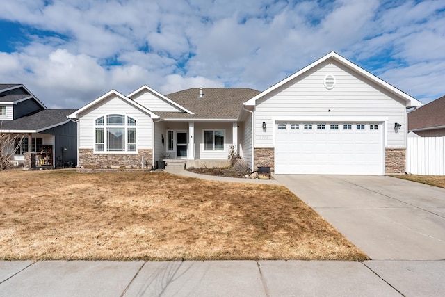 view of front facade featuring a shingled roof, fence, a garage, stone siding, and driveway