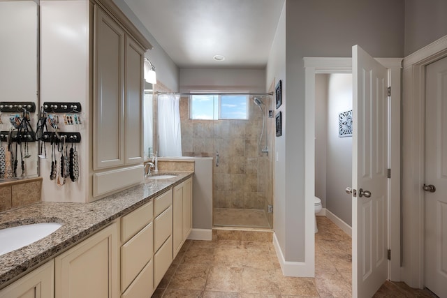 bathroom featuring double vanity, toilet, a sink, a shower stall, and baseboards