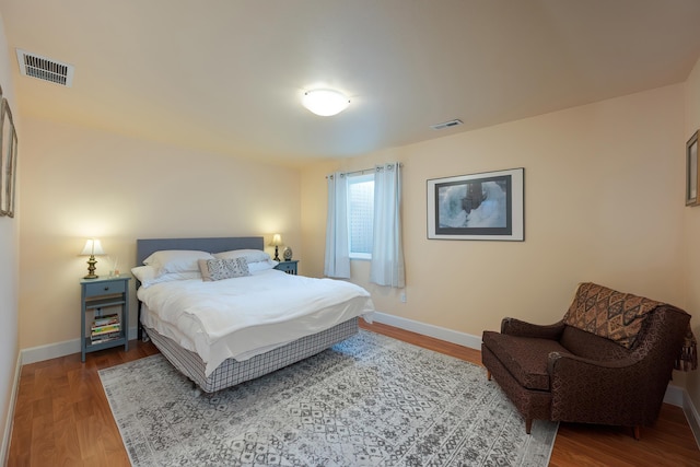 bedroom with baseboards, visible vents, and wood finished floors