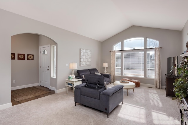 living area with light carpet, baseboards, arched walkways, and lofted ceiling