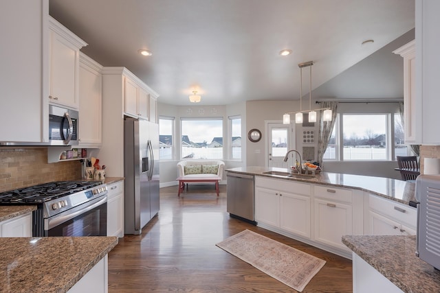 kitchen with stainless steel appliances, backsplash, a sink, and white cabinetry