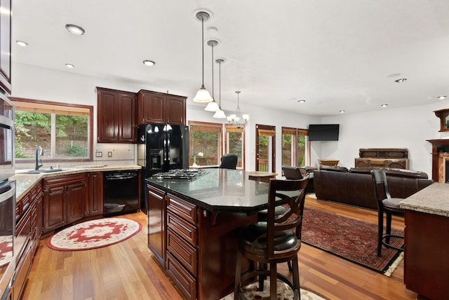 kitchen featuring black appliances, light wood finished floors, plenty of natural light, and a sink